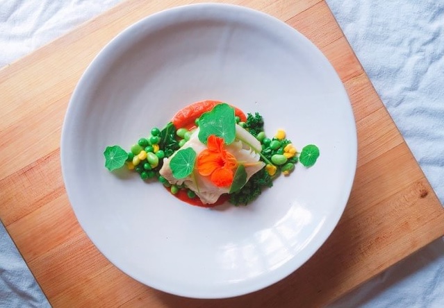 Cod with vegetables and red pepper puree in a bowl